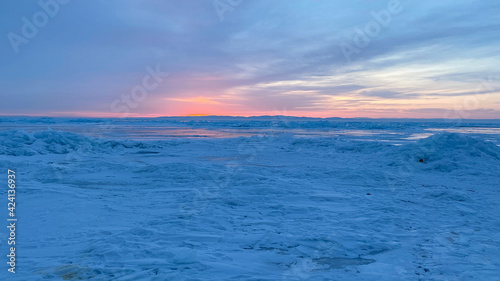 Amazing sunrise on the northern frosty Lake Baikal. Panorama of the northern landscape of the frozen lake.