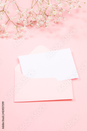 Pastel pink festive greeting card with empty white sheet in envelope and white gypsophila flowers. Copy space for text. © SeNata