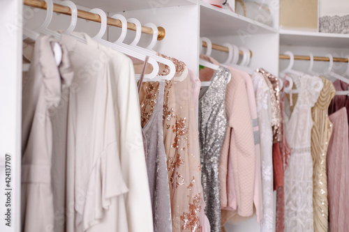 Beautiful female wardrobe. A lot of party dresses hanging on hangers in closet. Vintage clothing rental concept. Women's space. Large selection of various clothes. Small boutique showroom fashion shop © Antipina