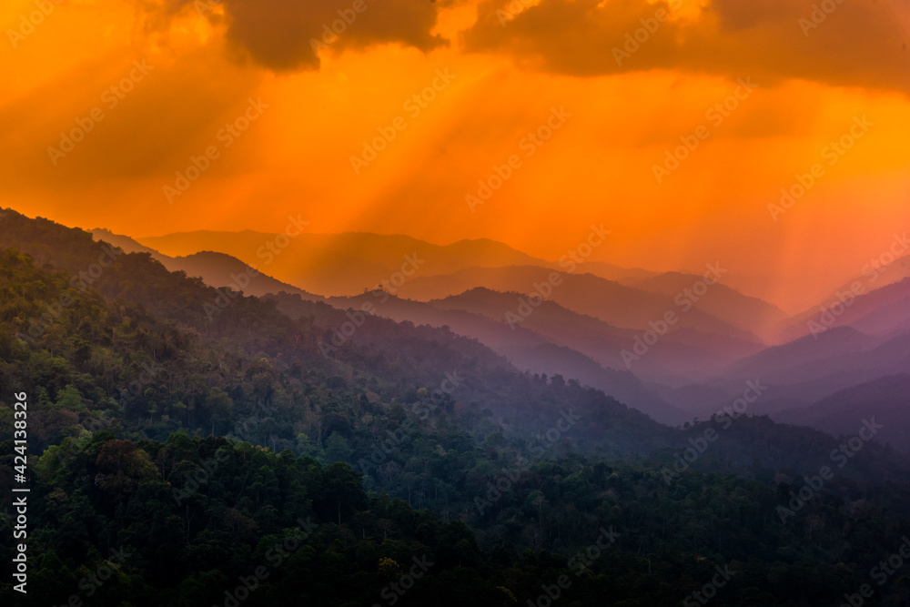 Tropical forest with mountains and majestic orange sky and clouds. Camping site at Maewong National Park, Nakhonsawan, Thailand.