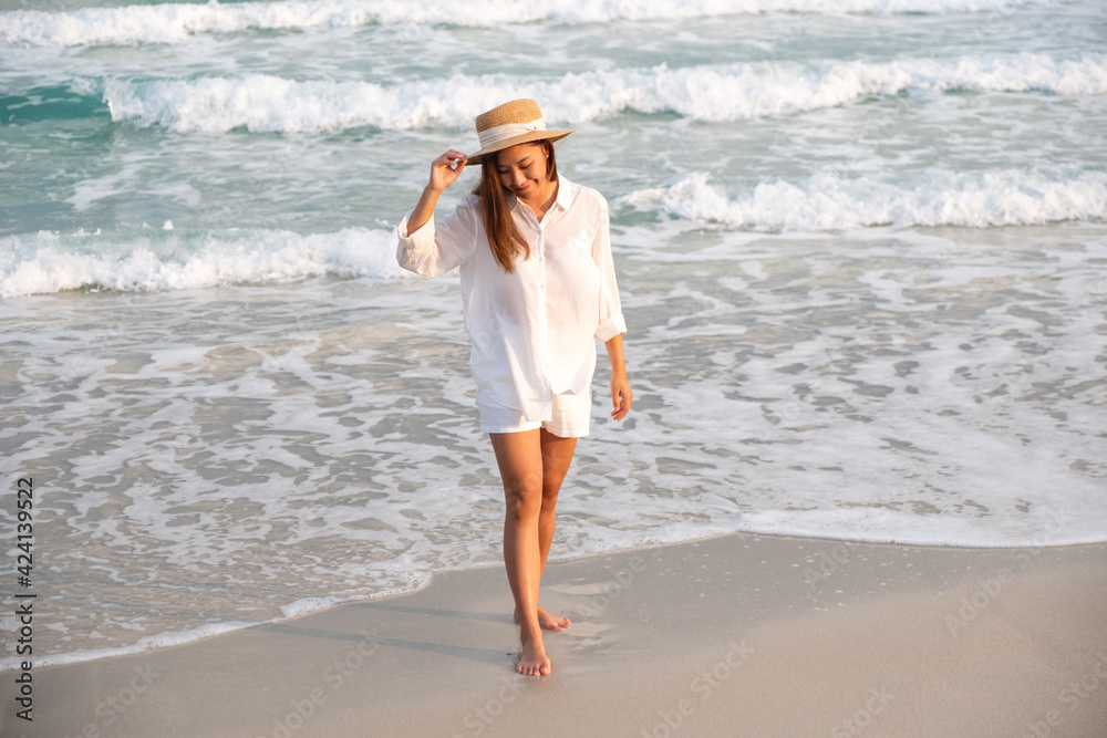 Portrait image of a beautiful young asian woman strolling on the beach by the sea