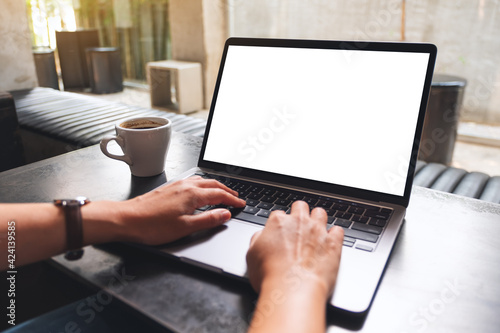 Mockup image of a woman using and typing on laptop computer with blank white desktop screen in cafe