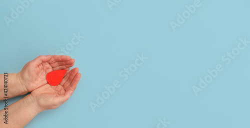 Hands women hold drop of blood on blue background.Concept of give blood donation, blood transfusion, world hemophilia day.World Health Day. Layout.Copy space.banner