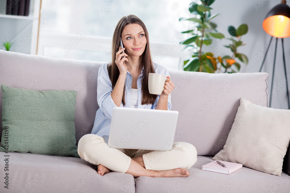 Full size photo of nice optimistic brunette long hairdo lady sit talk telephone laptop hold cup wear shirt at home Full size photo of nice optimistic brunette long hairdo lady sit talk telephone laptop hold cup wear shirt at home