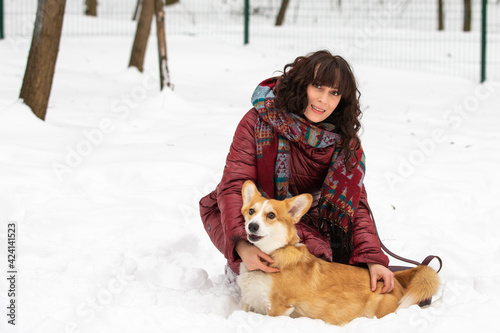 girl plays with cute welsh corgi in snow