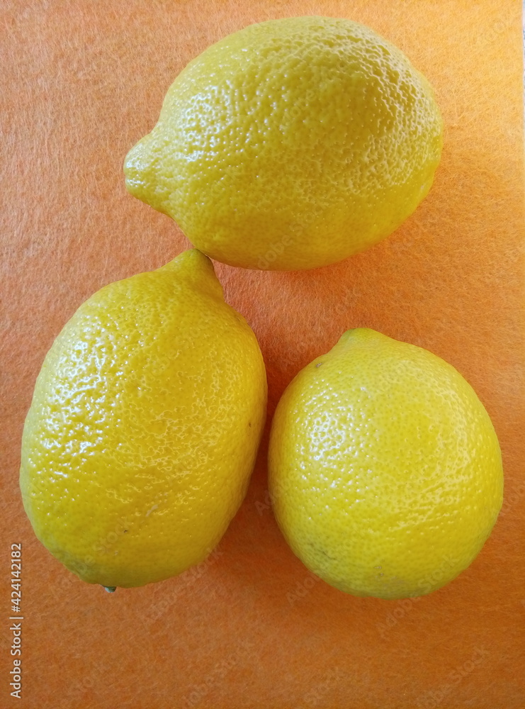 composition of juicy yellow lemons on an orange background