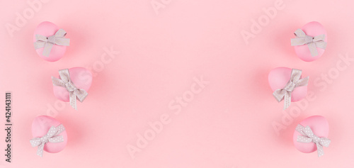Festive easter banner - pink easter eggs with silver bow as border on pastel pink backdrop. © finepoints