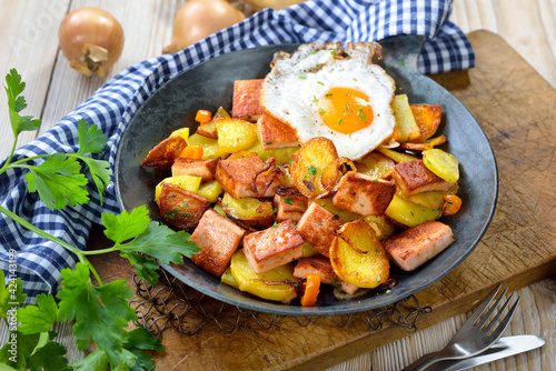 Deftiges bayerisches Leberkäs-Gröstl mit Bratkartoffeln und Spiegelei - Fried potatoes with meat loaf and a fried egg, so-called Bavarian groestl, often served in a frying pan