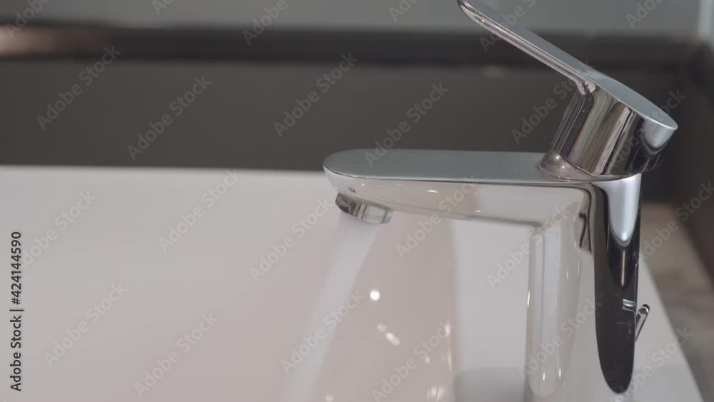 Close-up of hand opening the faucet in the bathroom. Close-up of hand opening the faucet in the bathroom.