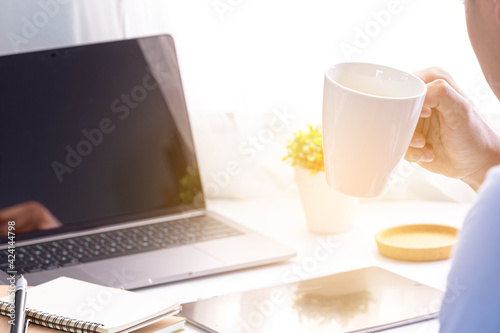 Businessman drinking coffee working and laptop on home office workspace