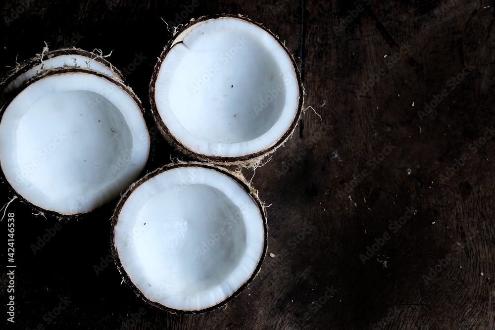 A group of a half cut of coconuts on old wooden table with dark background