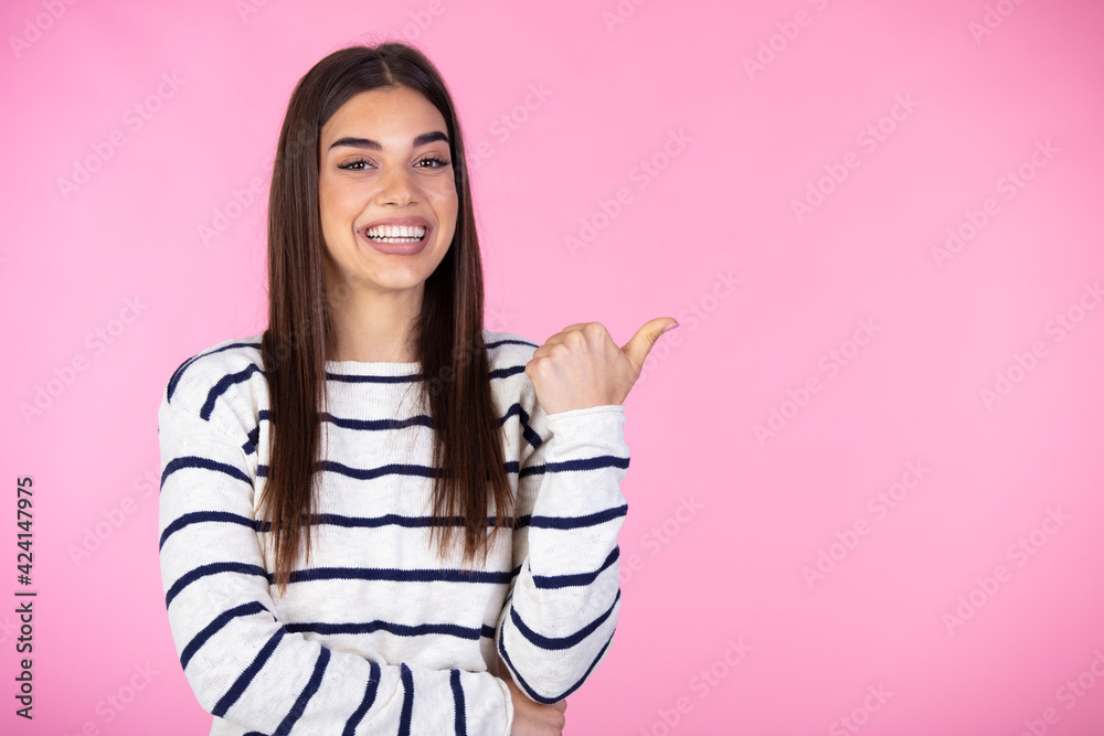 Horizontal shot of prettty young joyful female points with fore finger away, indicates copy space on blank wall, isolated over pink background. Check this out. Horizontal shot of prettty young joyful female points with fore finger away, indicates copy space on blank wall, isolated over pink background. Check this out.