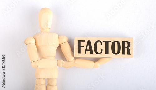 Wooden man shows with a hand to block with text FACTOR photo