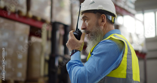Senior warehouse manager using walkie-talkie at workplace
