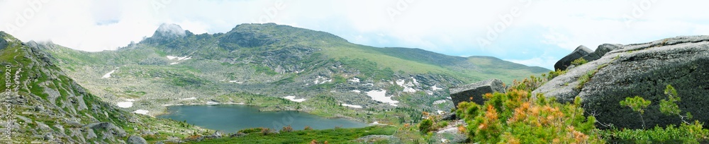 Panoramic view of the lake and the Parabola rock with a silhouette of a man in the natural park Ergaki, Russia. Summer landscape of the lake. Hike to the Western Sayan Panoramic view of the lake and the Parabola rock with a silhouette of a man in the natural park Ergaki, Russia. Summer landscape of the lake. Hike to the Western Sayan
