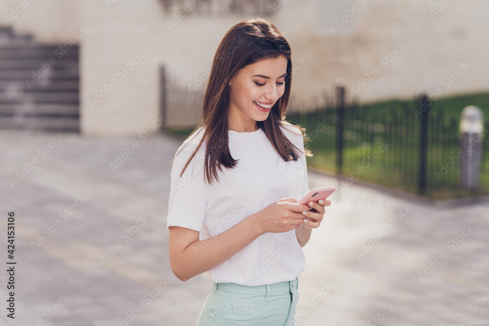 Profile photo of optimistic brunette lady look telephone wear white t-shirt walking in park outside