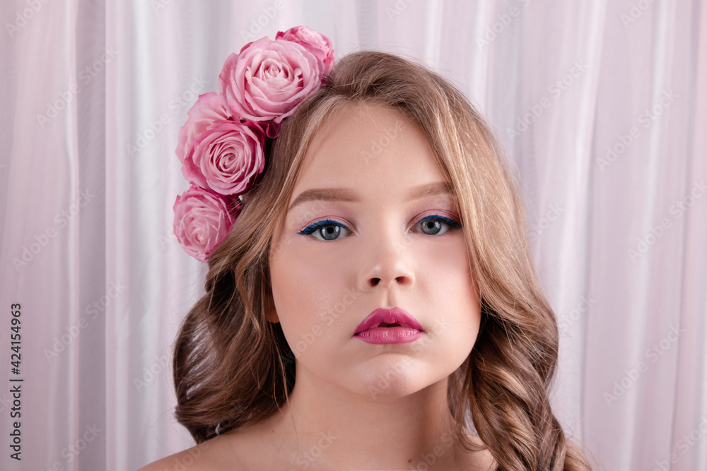 teenage girl with pink roses in her hair on pink silk background. flowers in curls. fashion photo. spring or summer flowering teenage girl with pink roses in her hair on pink silk background. flowers in curls. fashion photo. spring or summer flowering