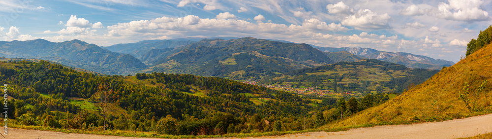 Wide panorama of a small romanian village surrounded by green hills and mountains, Salciua, Dumesti