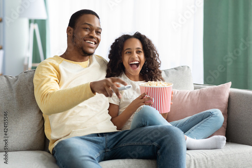 Joyful black family father and daughter watching movie together