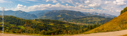 Fototapeta Naklejka Na Ścianę i Meble -  Wide panorama of a small romanian village surrounded by green hills and mountains, Salciua, Dumesti