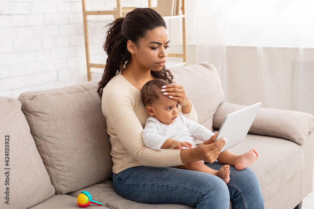 Black Mother With Sick Baby Using Tablet Sitting At Home Black Mother With Sick Baby Using Tablet Sitting At Home