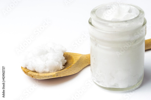 Unrefined coconut oil on a white background with wooden spoon