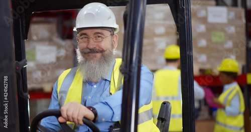Happy engineer operating forklift truck in warehouse