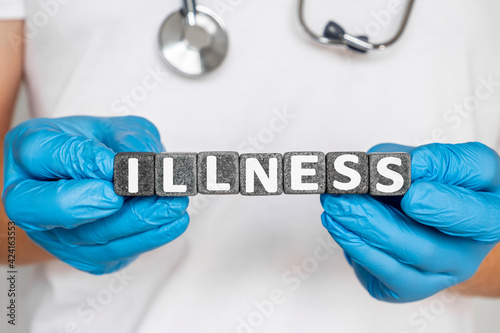 illnes - word from stone blocks with letters holding by a doctor's hands in medical protective gloves. disease or period of sickness affecting the body or mind.