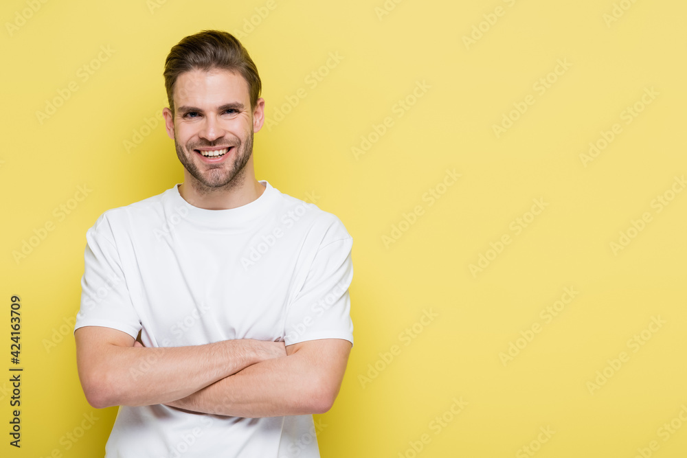 happy man smiling at camera while standing with crossed arms on yellow happy man smiling at camera while standing with crossed arms on yellow