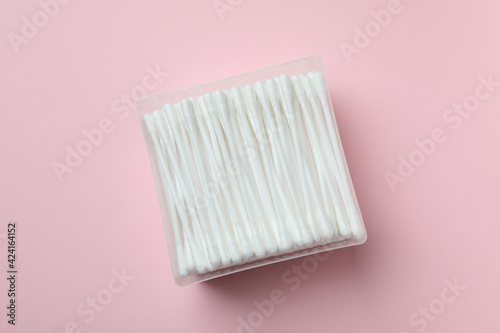 Plastic box with cotton swabs on pink background