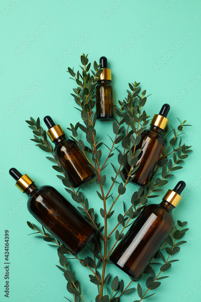 Brown bottles of eucalyptus oil and branch on mint background Brown bottles of eucalyptus oil and branch on mint background