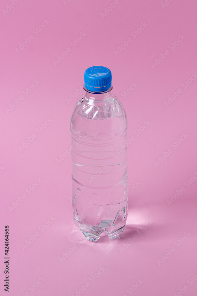 Water bottle on a pink background. Plastic bottle with water. Clean drinking water. Water bottle on a pink background. Plastic bottle with water. Clean drinking water.
