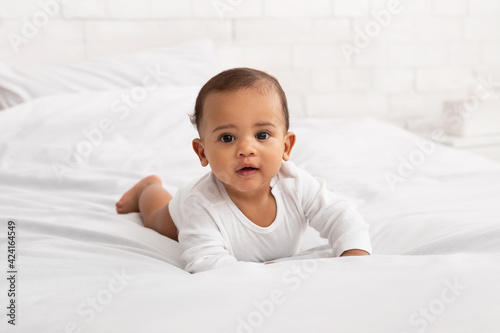 Adorable Black Baby Toddler Crawling On Bed In Bedroom Indoor