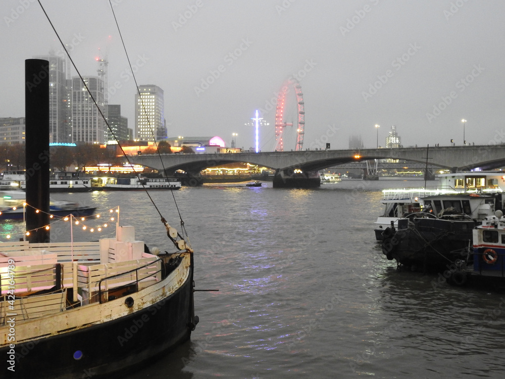 Buildings, bridge and boats on the river Thames in fog