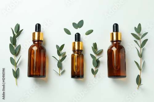 Brown bottles of eucalyptus oil and twigs on white background