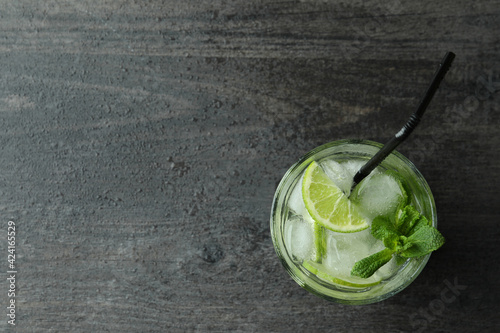 Glass of mojito cocktail on dark wooden background