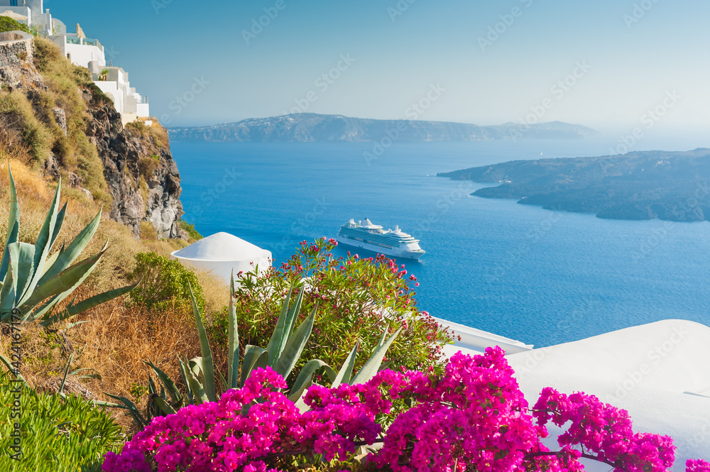 Fototapeta premium White architecture on Santorini island, Greece. Flowers on the terrace with sea view. Travel destinations concept