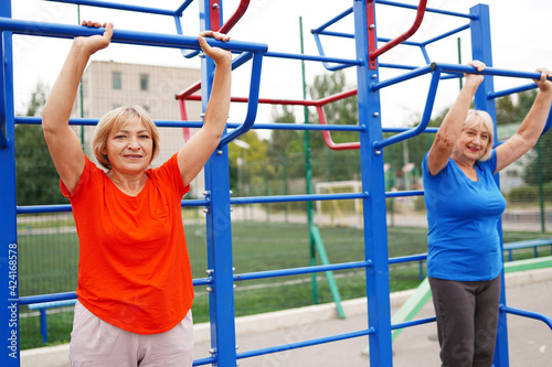 two adult women 58 and 64 years old doing exercises outdoors on the stadium
