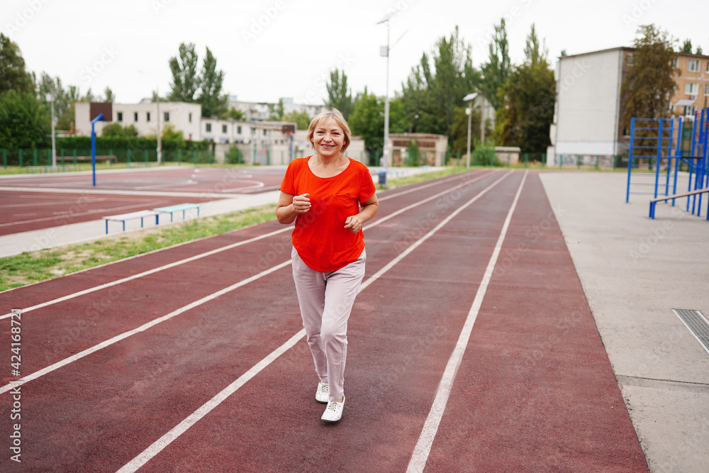 elderly woman running in early morning. Attractive looking mature woman keeping fit and healthy.