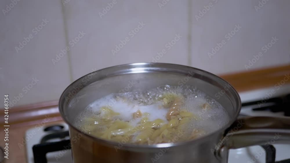 Cooking pasta, spaghetti in boiling water in the home kitchen. Bubbles, splashes in the saucepan. Preparing a quick lunch, dinner in the home kitchen. Food concept. 4K. Close up. Slow motion. Cooking pasta, spaghetti in boiling water in the home kitchen. Bubbles, splashes in the saucepan. Preparing a quick lunch, dinner in the home kitchen. Food concept. 4K. Close up. Slow motion.