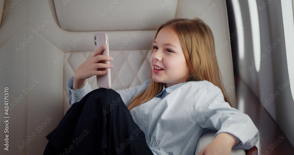 Fototapeta premium Kid with mobile phone in airplane in window seat.