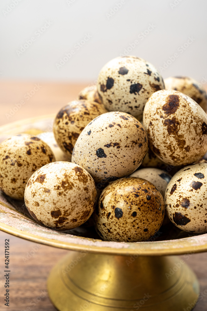 Fototapeta premium Fresh small spotted partridge eggs on bronze plate