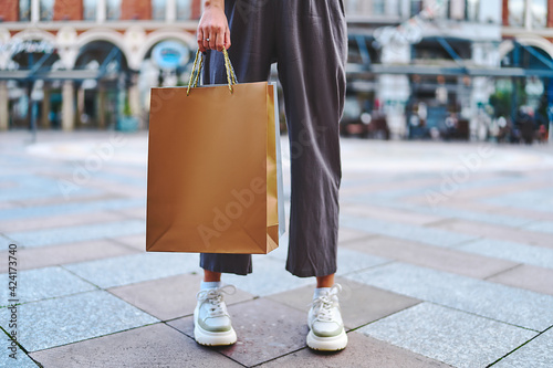 Stylish fashionable woman shopaholic with paper shopping bags walks in the center of a european city during black friday sales week