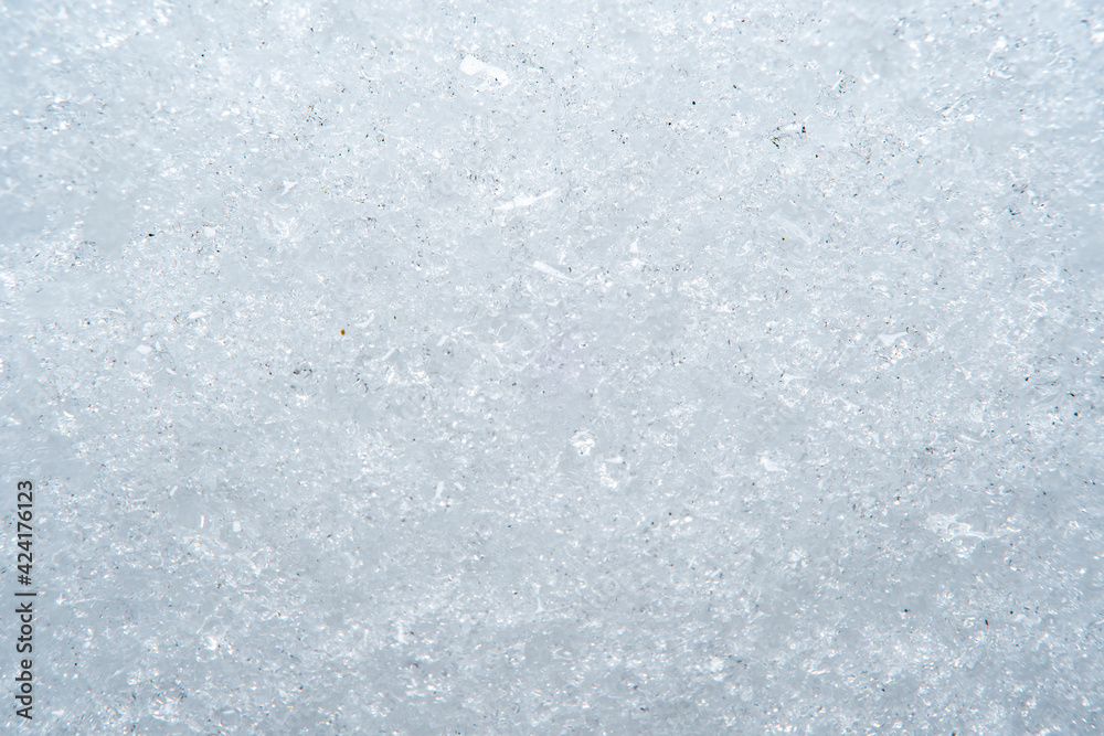 Background with close-up of snow under strong magnification. Slightly melted snow with sharp edges in soft focus.