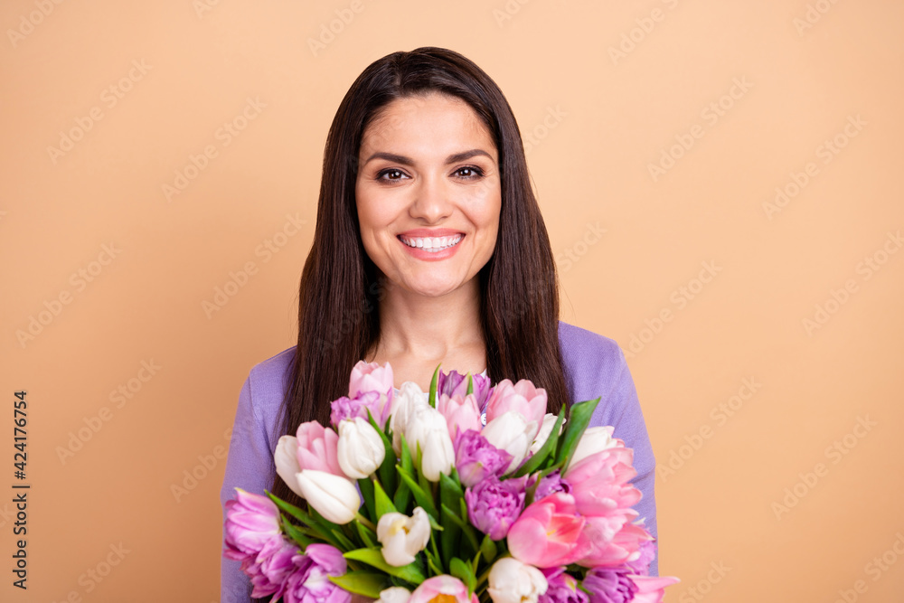 Photo of cheerful attractive woman happy positive smile hold flower bouquet isolated over beige color background Photo of cheerful attractive woman happy positive smile hold flower bouquet isolated over beige color background