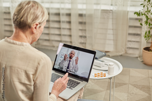 An elderly woman communicates remotely via a laptop with her doctor. Telemedicine concept