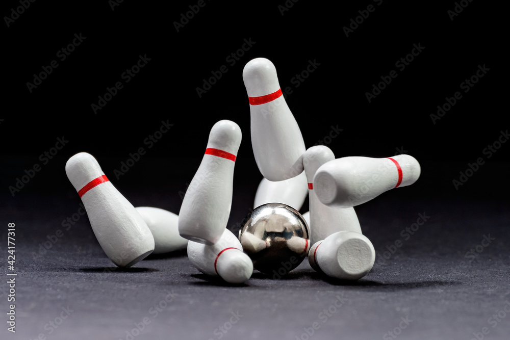 Bowling. Bowling ball knocks down pins on a black background. Copy space. Space for text Bowling. Bowling ball knocks down pins on a black background. Copy space. Space for text