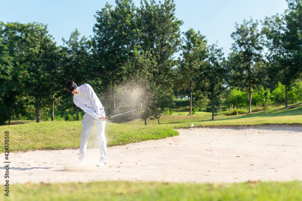 Asia Golfer man hitting out of a sand trap. The golf course is on the sand. Hobby in holiday and vacations on club golf. Lifestyle and Sport Concept Asia Golfer man hitting out of a sand trap. The golf course is on the sand. Hobby in holiday and vacations on club golf. Lifestyle and Sport Concept