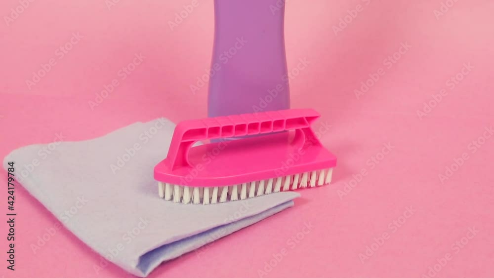 Close-up of a plastic jar of cleaning agent, a cleaning cloth, and a pink cleaning brush. The concept of cleaning the house and chores around the house. Close-up of a plastic jar of cleaning agent, a cleaning cloth, and a pink cleaning brush. The concept of cleaning the house and chores around the house.