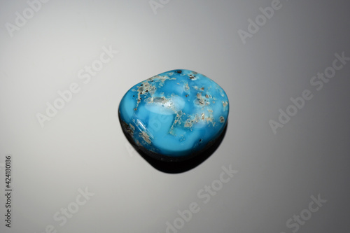 Loose natural Kingman mine turquoise cabochon setting stone from Arizona. American free form hand cut, polished gemstone. Beautiful pattern. Gray radial gradient background.